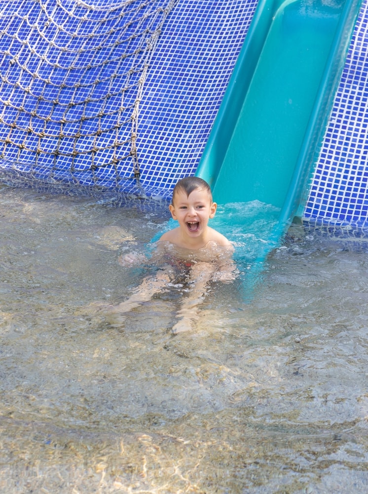 Happy,Child,Slides,Down,The,Slide,In,The,Water,Park